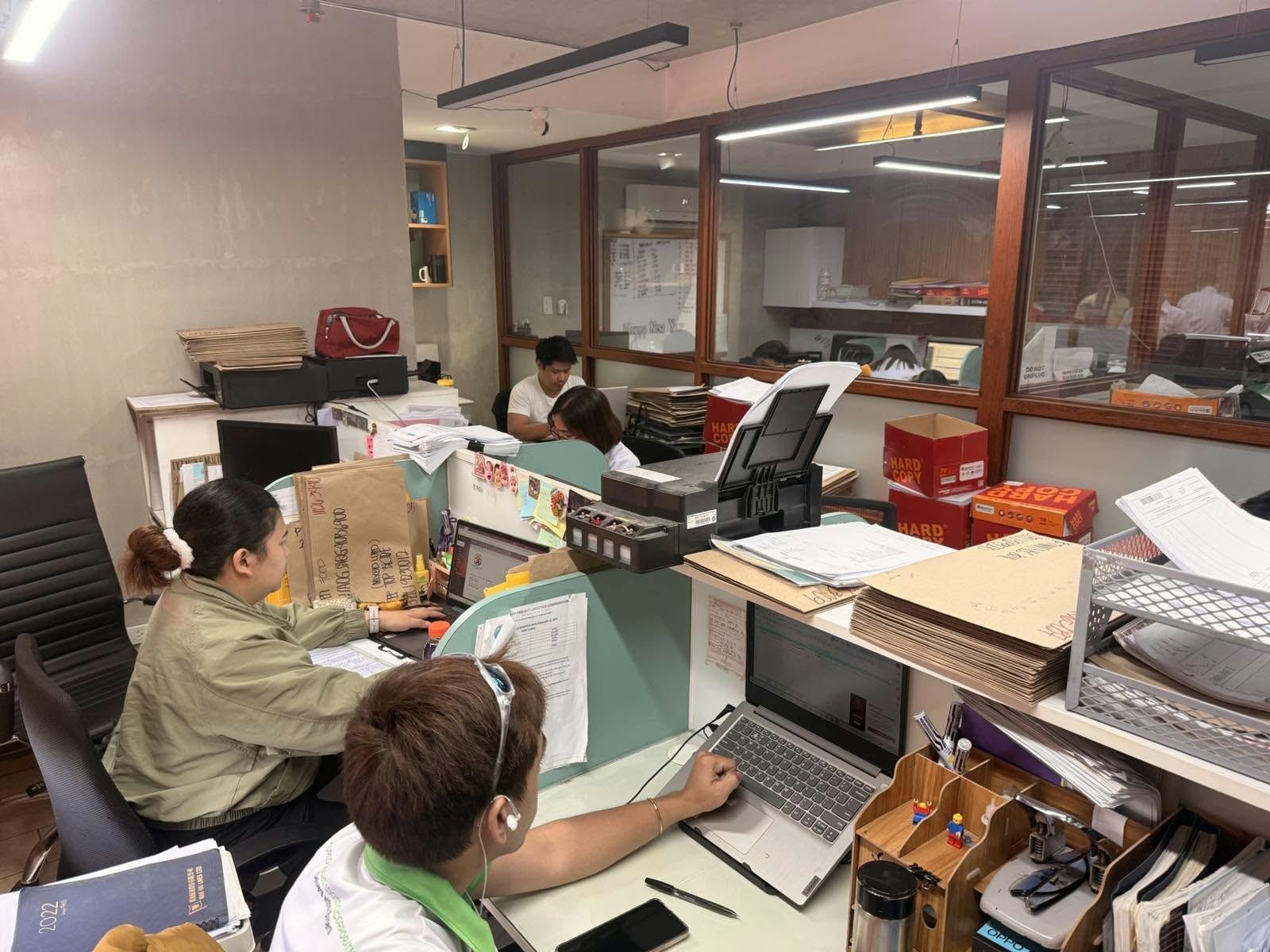 Staff processing documents at glass-partitioned desks